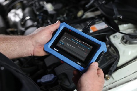 Mechanic diagnosing vehicle issues with an instrument